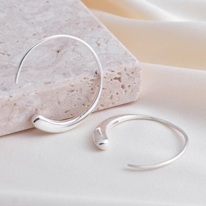 May include: A pair of silver hoop earrings with a unique curved design. The earrings are simple and elegant, and would make a great addition to any jewelry collection.