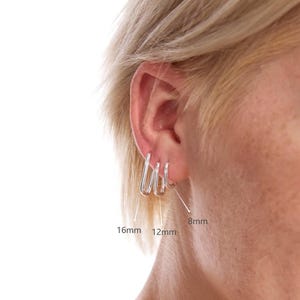 May include: Three silver hoop earrings in different sizes: 8mm, 12mm, and 16mm. The earrings are shown on a person's ear.