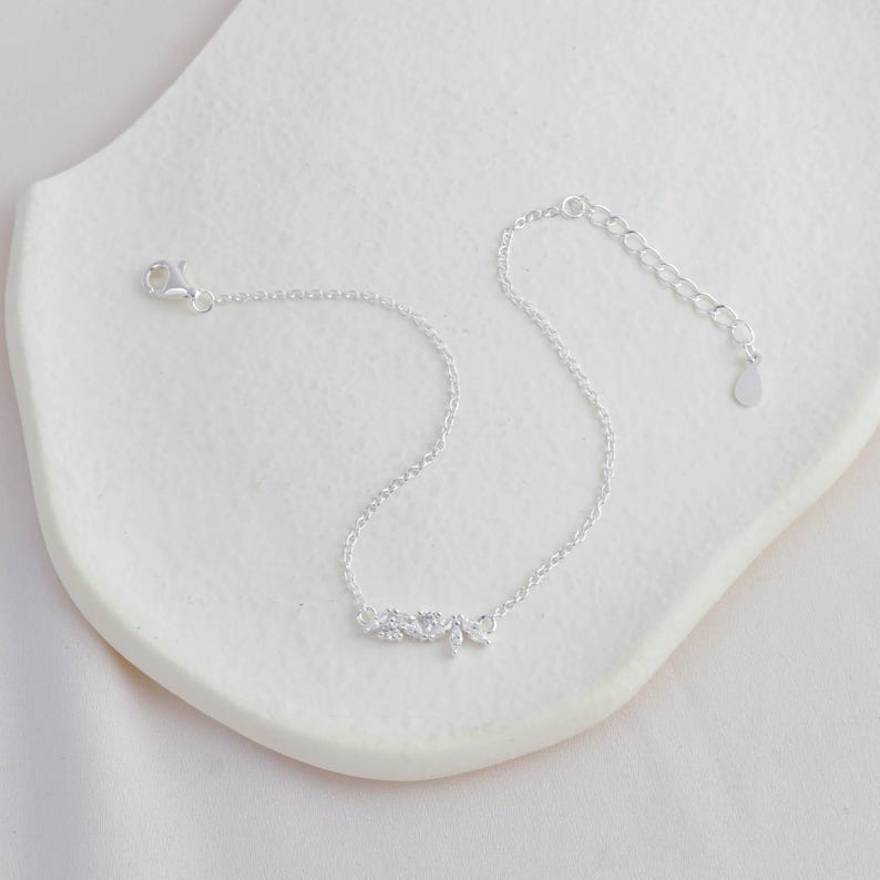 May include: A silver chain bracelet with a small, sparkling word "love" charm.