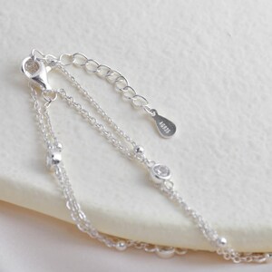 Puede incluir: Un brazalete de cadena de plata con un dise&ntilde;o delicado. El brazalete presenta peque&ntilde;as piedras transparentes y una etiqueta de plata con la inscripci&oacute;n "AG925".