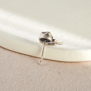 May include: A silver cat-shaped stud earring with a black stone in the center.