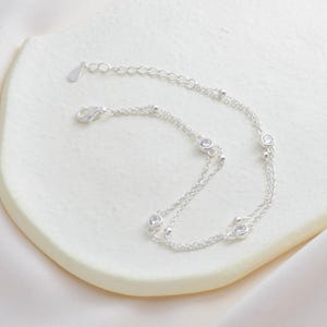 Puede incluir: Un brazalete de cadena de plata con peque&ntilde;as piedras transparentes. El brazalete tiene un dise&ntilde;o delicado y es perfecto para el uso diario.