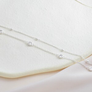 Puede incluir: Un delicado collar de cadena de plata con peque&ntilde;as piedras de circonita c&uacute;bica transparentes. El collar tiene un dise&ntilde;o en capas con dos cadenas.