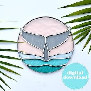 May include: A stained glass whale tail design with a pink, grey, white, and turquoise colour scheme. The whale tail is in the centre of the circle, with the turquoise representing the water.