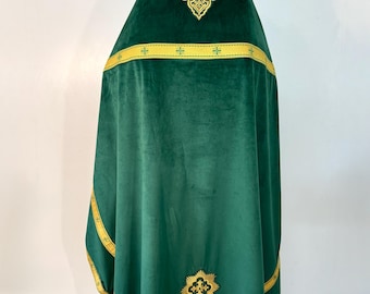May include: A dark green liturgical vestment with gold embroidered details. The vestment features a gold cross design at the top and bottom, with gold trim along the edges. The fabric appears to be a soft velvet.
