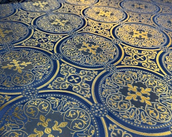 Puede incluir: Un rollo de tela con un patrón repetitivo de grandes círculos azules que contienen intrincados motivos florales y de cruces doradas. El fondo es azul oscuro y el diseño se compone de formas circulares y cuadradas doradas entrelazadas.