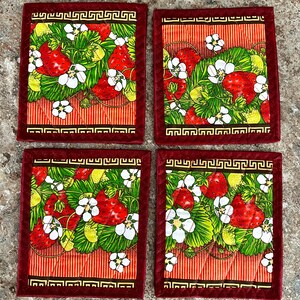 May include: Set of four square coasters featuring a vibrant strawberry design. Each coaster has a red border with a Greek key pattern, surrounding a pattern of red strawberries, green leaves, and white flowers on a striped background.