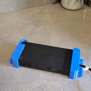 May include: A black Dell computer with a blue plastic wall mount. The computer has multiple ports on the back.