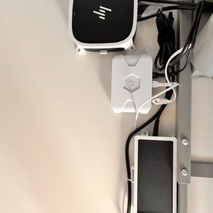 以下が含まれることがあります： 黒と白のHPブランドのユニット、白いUbiquitiデバイス、黒い長方形のコンポーネントなど、取り付けられた電子デバイスのコレクション。 ケーブルとワイヤーはきちんと整理されており、ネットワークまたはデータ設定を示唆しています。