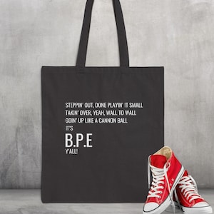 May include: Black tote bag with white text that reads "STEPPIN' OUT, DONE PLAYIN' IT SMALL TAKIN' OVER, YEAH, WALL TO WALL GOIN' UP LIKE A CANNON BALL IT'S B.P.E Y'ALL!"