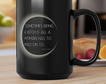 Taza negra con diseño de eclipse y cita de Dolores Claiborne: «A veces, ser una perra es lo único a lo que una mujer puede aferrarse» / Stephen King Horror