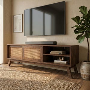 Puede incluir: Un mueble de TV de estilo moderno de mediados de siglo en un acabado marrón cálido. El mueble cuenta con puertas correderas con inserciones de caña tejida y estanterías abiertas. Un televisor de pantalla plana grande está montado encima, con una barra de sonido debajo. Una planta en maceta y arte enmarcado completan la habitación.