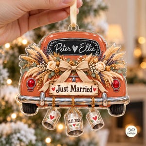 Peut inclure: Une décoration en acrylique transparent en forme d'arrière de voiture vintage orange. Elle présente une plaque style ardoise avec "Peter Ellie" et un cœur, un panneau "Just Married", des fleurs séchées, un nœud en toile de jute et trois boîtes de conserve suspendues avec des cœurs et "10.11.2026".