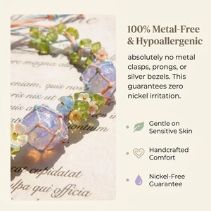 May include: A close-up of a handcrafted, metal-free necklace with light blue, green, and white accents. The necklace features a delicate design with small flowers and beads. The text reads "100% Metal-Free & Hypoallergenic."