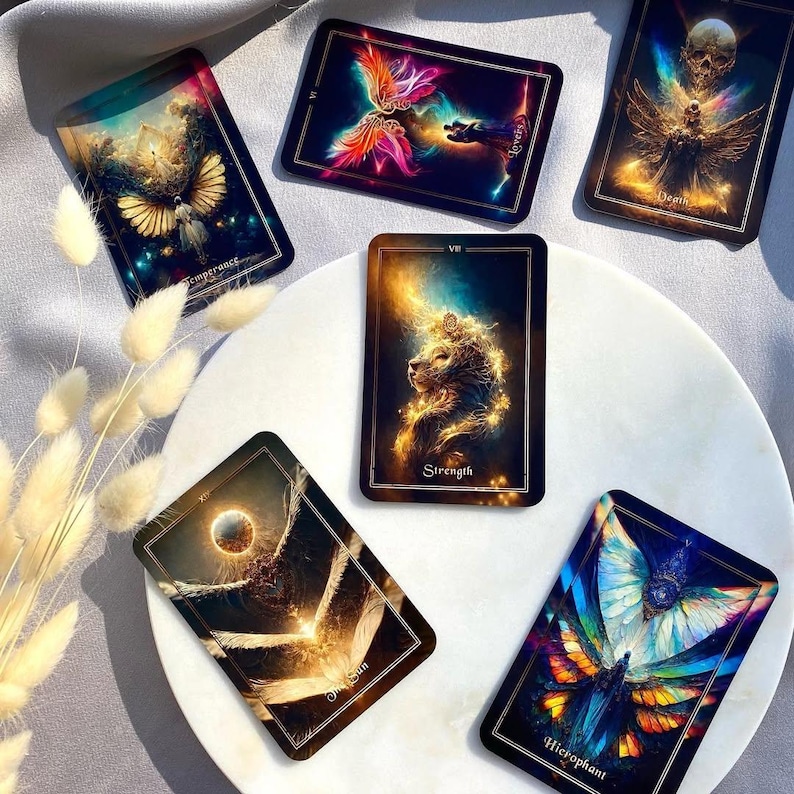 Pode incluir: Um conjunto de cartas de tarot com ilustra&ccedil;&otilde;es vibrantes. As cartas exibem imagens de anjos, borboletas e corpos celestes, com t&iacute;tulos como "Temperan&ccedil;a", "Amantes" e "For&ccedil;a". As cartas est&atilde;o dispostas sobre uma superf&iacute;cie branca.