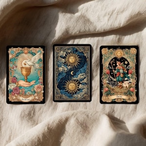 Pode incluir: Tr&ecirc;s cartas de tarot com bordas ornamentadas e ilustra&ccedil;&otilde;es detalhadas. Uma carta apresenta uma pomba acima de um c&aacute;lice, outra mostra s&oacute;is e nuvens, e a terceira retrata uma figura com um c&atilde;o. As cartas t&ecirc;m uma est&eacute;tica vintage.