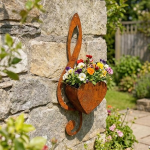 May include: A rusty metal treble clef-shaped planter filled with colorful flowers, mounted on a stone wall. The planter has a heart-shaped container holding a variety of blooms in shades of red, yellow, purple, and white.