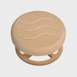 Peut inclure: Tabouret en bois clair avec une assise ronde ornée de trois rainures incurvées. Le tabouret possède une base circulaire avec des découpes. Design simple et minimaliste. Fabriqué en bois naturel.