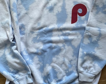 May include: A light blue tie-dye sweatshirt with a maroon embroidered letter "P" on the front.
