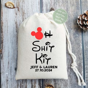 Puede incluir: Una bolsa de tela blanca con una cabeza de Mickey Mouse roja y el texto "Oh Shit Kit" en negro. Debajo del texto est&aacute; "Jeff & Lauren 27.10.2024" en negro.