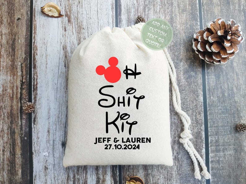 Puede incluir: Una bolsa de tela blanca con una cabeza de Mickey Mouse roja y el texto "Oh Shit Kit" en negro. Debajo del texto est&aacute; "Jeff & Lauren 27.10.2024" en negro.