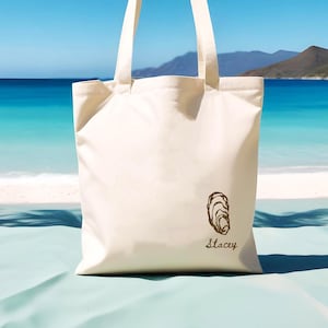 May include: A white canvas tote bag with a brown oyster illustration and the name "Stacey" printed on the front.