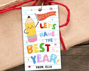 May include: A rectangular gift tag with a white lined paper background featuring a cartoon yellow pencil holding an orange flag that says BACK TO SCHOOL. The text reads LET'S HAVE THE BEST YEAR in colorful letters with FROM, ELLA at the bottom.
