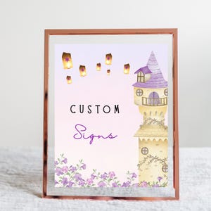 May include: A framed print with a watercolor illustration of a tower and floating lanterns. The text "CUSTOM Signs" is displayed in black and purple. The frame is rose gold.