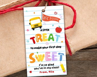 May include: A rectangular gift tag with a white lined paper background featuring a yellow school bus, a red apple, and a yellow pencil. The text reads: Back to School, A little TREAT to make your first day SWEET, I'm so glad you're in my class!, From, Ella.