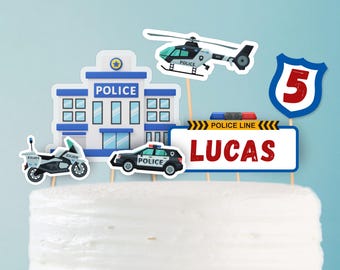 Könnte beinhalten: Kuchenaufsatz mit Polizeimotiv, einschließlich Polizeistation, Auto, Motorrad und Hubschrauber. Ein Schild zeigt die Zahl 5. Der Aufsatz hat ein Schild mit dem Namen "LUCAS" in Rot. Das Design verwendet Blau, Weiß und Schwarz.