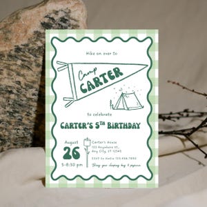 Puede incluir: Una invitación con estampado de cuadros verdes y blancos para una fiesta de cumpleaños con temática de campamento. La invitación presenta el texto "Camp Carter" en un diseño de banderín, junto con la fecha, hora y lugar de la fiesta. También incluye un dibujo de una tienda de campaña y una nube de azúcar.