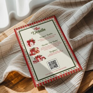 May include: A rectangular baby shower invitation card with a red and green border featuring Christmas-themed illustrations of gifts and a teddy bear. The text includes The Details, Diaper Raffle, Books For Baby, Registry, and a QR code for scanning.