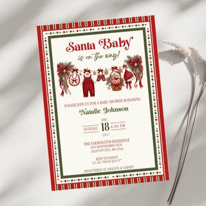 May include: A rectangular baby shower invitation with a red and green border. The text reads Santa Baby is on the way! honoring Natalie Johnson on Sunday, Dec 18, 2027, at 6:00 PM at The Farmington Residence, 5505 Montgomery Run, Ellicott City, MD 21544.