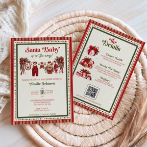 May include: Two rectangular baby shower invitation cards with a cream background, red and green borders, and festive illustrations. The text reads Santa Baby is on the way, honoring Natalie Johnson, and includes event details, a QR code, and registry info.