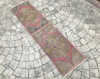 May include: A vintage runner rug with a traditional Persian design in shades of red, pink, gold, and brown. The rug has a distressed look and is perfect for adding a touch of bohemian style to your home.