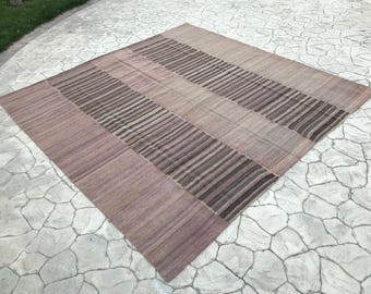 May include: A rectangular rug with a striped pattern in shades of brown and beige. The rug is woven with a subtle texture and has a distressed, vintage look.