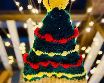 Peut inclure: Un bonnet de Noël en crochet vert, rouge et jaune avec un pompon jaune sur le dessus.