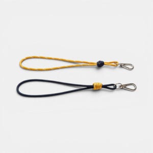 May include: Two wrist lanyards made of cord, one in yellow with a dark blue knot and one in dark blue with a yellow knot. Each lanyard features a silver-toned metal lobster clasp at the end, providing a secure attachment point for small items.