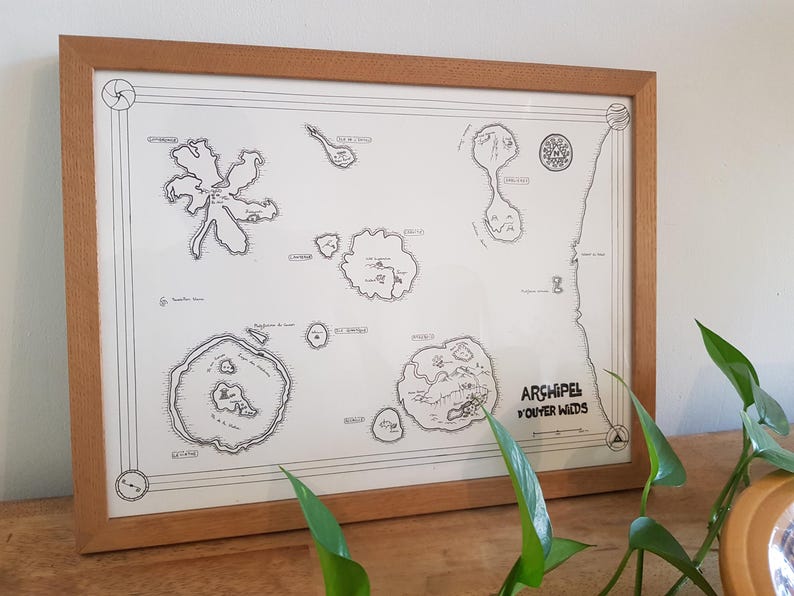 May include: A framed black and white map titled 'Archipel D'Outer Wilds' with a compass rose in the top left corner and a variety of islands and land masses. The map is surrounded by a light brown wood frame.