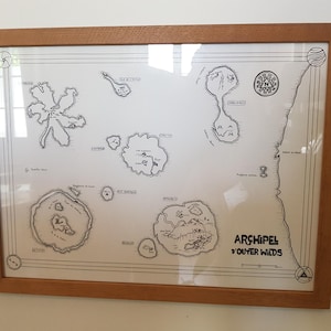 May include: A framed black and white map titled 'Archipel d'Outer Wilds' with various islands and names of locations. The map is on a white background and is framed in a light brown wood frame.