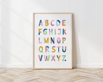 May include: A framed alphabet print featuring colorful letters A through Z. Each letter is a different color and pattern, including blue, orange, pink, and green. The print is displayed on a white background with a light wood frame.