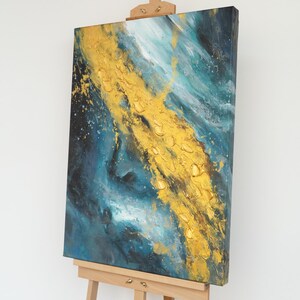 Puede incluir: Arte abstracto en lienzo con un diseño texturizado en oro y turquesa. La obra presenta una franja dorada central con pintura texturizada, sobre un fondo de remolinos turquesa y azul oscuro. El lienzo se exhibe sobre un caballete de madera.