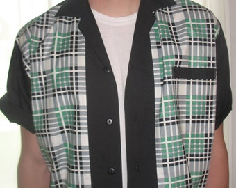 May include: A black and white plaid shirt with a black collar and buttons. The shirt has a green and white plaid pattern on the front and a solid black back.