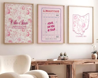 Può includere: Tre stampe artistiche incorniciate con disegni floreali e di testo. La prima stampa dice "Ohio State University" in rosa. La seconda stampa è un design di scheda della biblioteca con testo. La terza stampa è un contorno rosa dell'Ohio con testo che dice "Columbus, Ohio".
