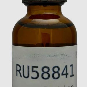 May include: A brown glass bottle with a black dropper and cap. The bottle has a white label with the text "RU58841 solution" and "Research use only."