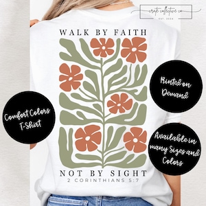 Puede incluir: Camiseta blanca Comfort Colors con un diseño floral en naranja y verde. El texto "WALK BY FAITH" y "NOT BY SIGHT" están encima y debajo del diseño floral. El texto "2 CORINTIOS 5:7" está debajo.