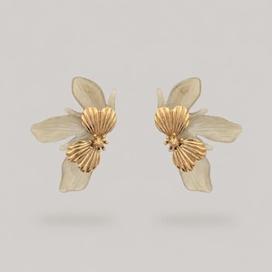 May include: A pair of stud earrings featuring a gold-toned metal flower center with ribbed petal details, layered over translucent, pale grey, organic-shaped petals that extend outward to create a layered, dimensional floral appearance.