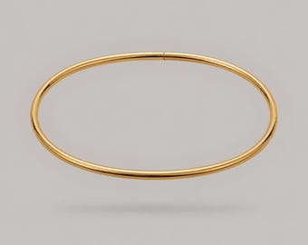 Puede incluir: Una pulsera tipo brazalete circular y delgada en oro con un acabado liso y pulido. La pieza de joyería presenta un diseño simple de aro continuo con una costura sutil visible en la parte superior, mostrando una superficie metálica brillante.