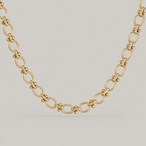 May include: A gold-toned chain necklace featuring a series of repeating oval links. Each oval link is connected by a small, horizontal bar flanked by two tiny spheres on either side, creating a uniform and structured metallic link pattern.