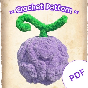 Könnte beinhalten: Eine gehäkelte lila Frucht mit einem grünen Stiel, die einer stilisierten Beere ähnelt. Das Bild enthält den Text "Crochet Pattern" und "PDF" in einem kreisförmigen Design, was auf ein herunterladbares Muster hindeutet.